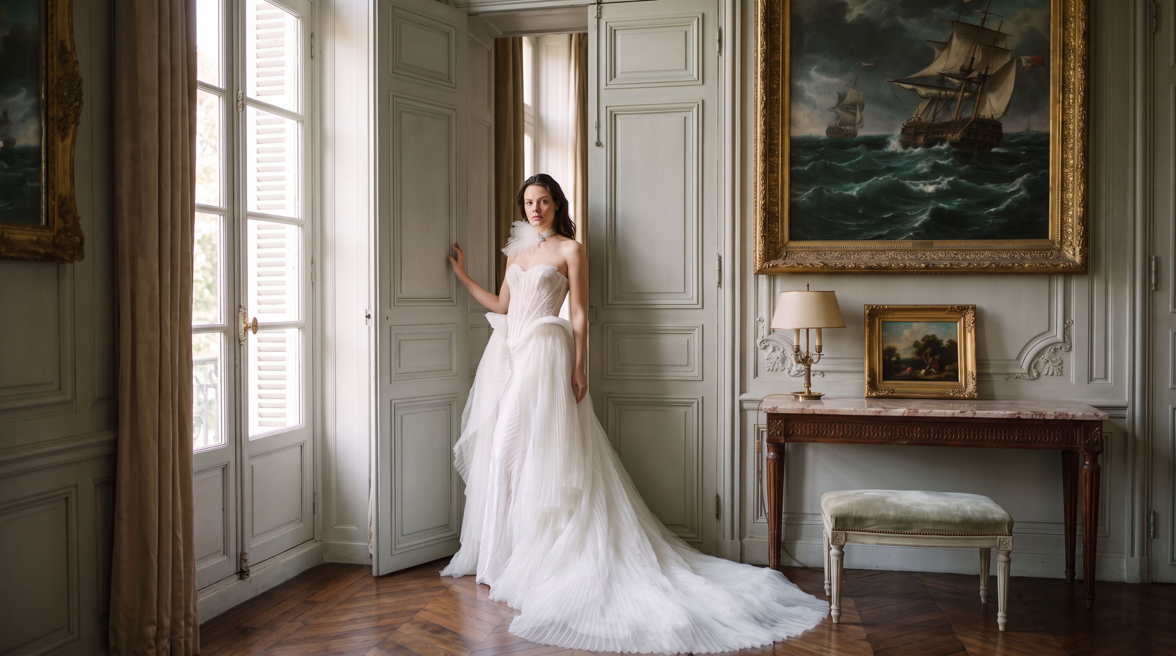 Bride in a strapless A-line gown with a long train, beside tall shuttered windows in a panelled room