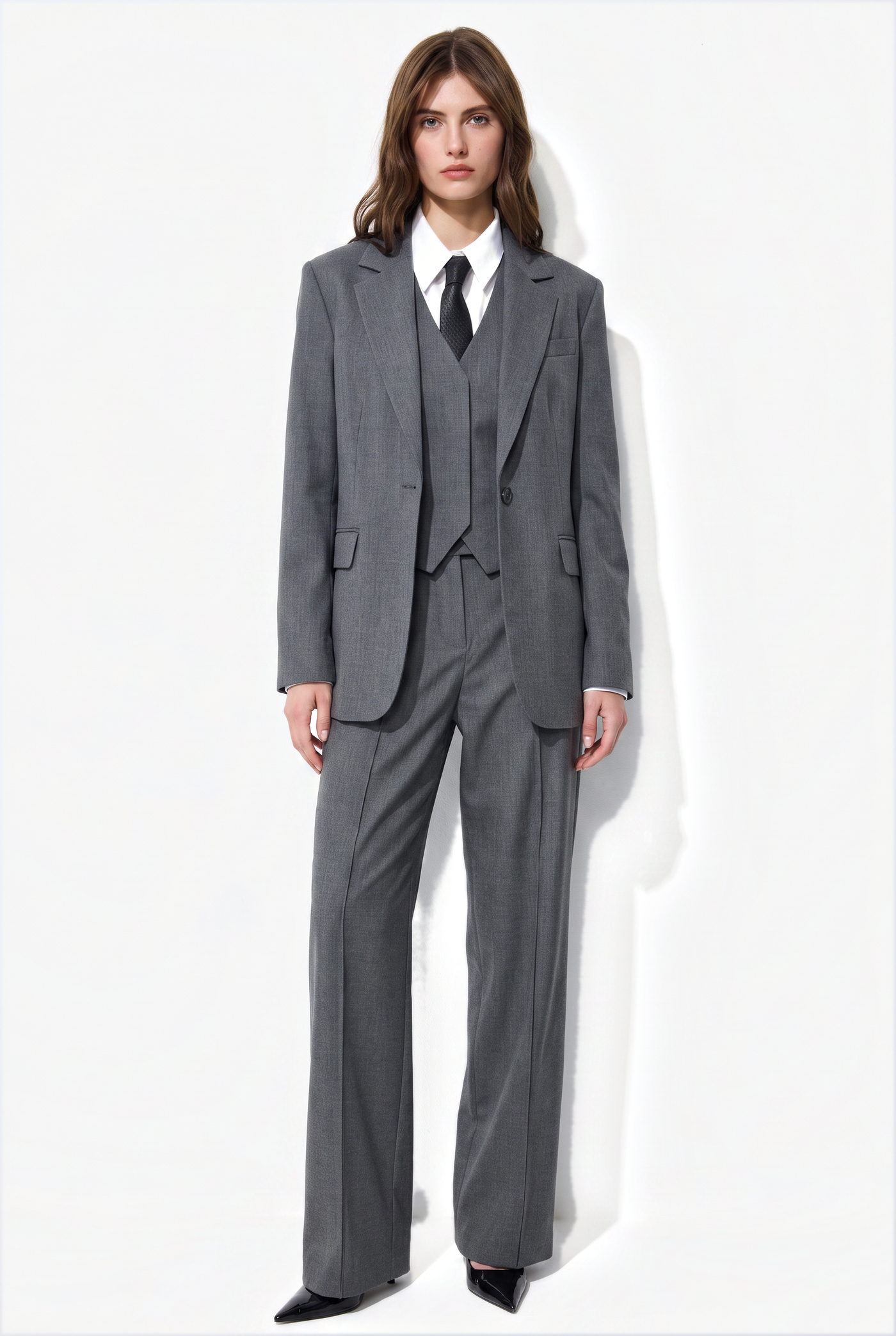 Woman in a grey three piece suit with a white shirt and dark tie