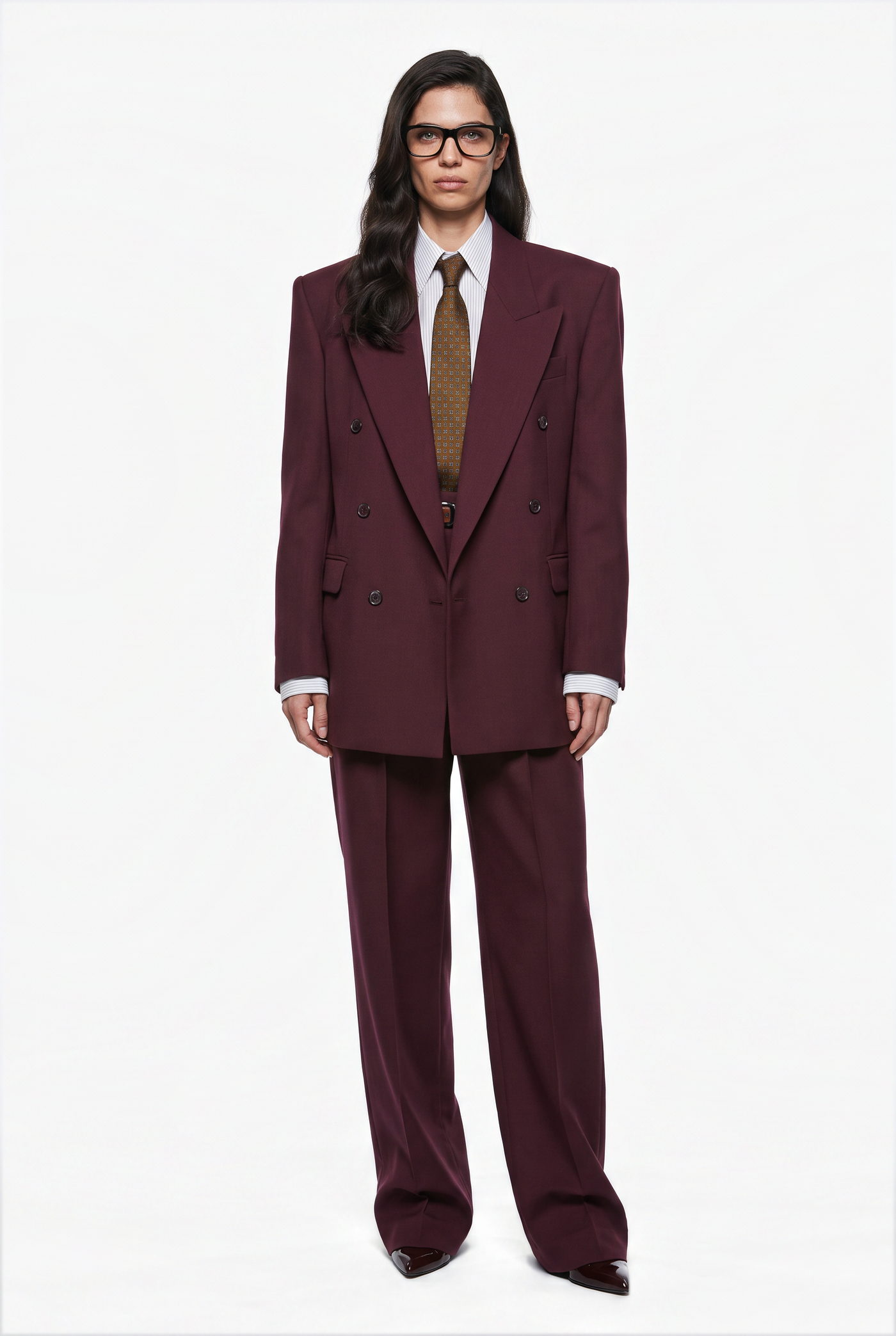 Woman in a burgundy suit with a white shirt and brown tie