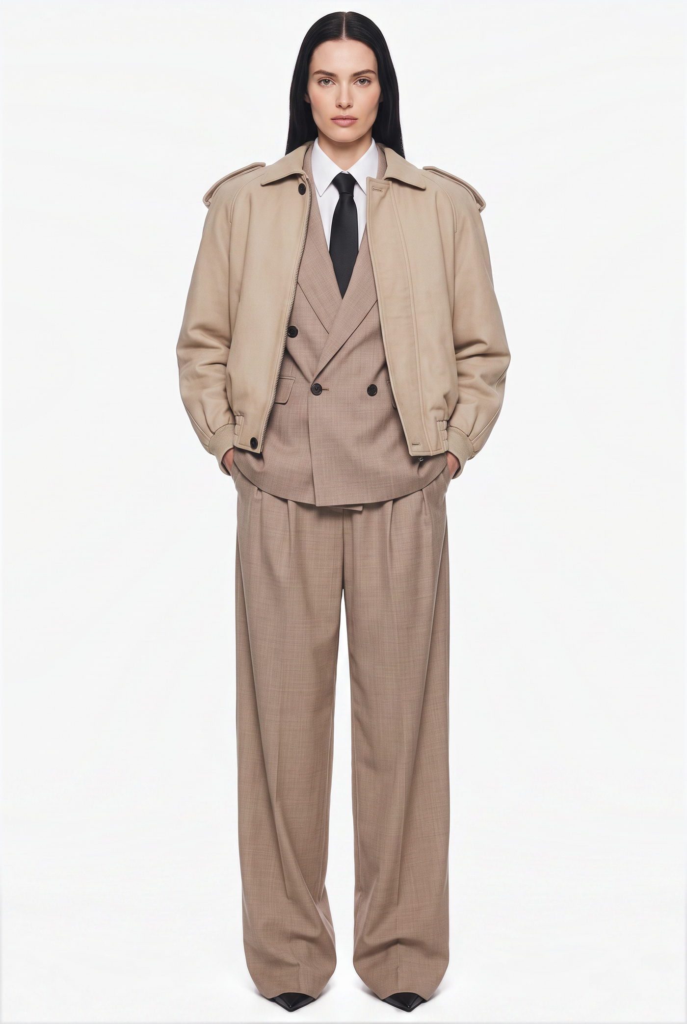 Woman in a tan double breasted suit under an oversized beige coat with a dark tie