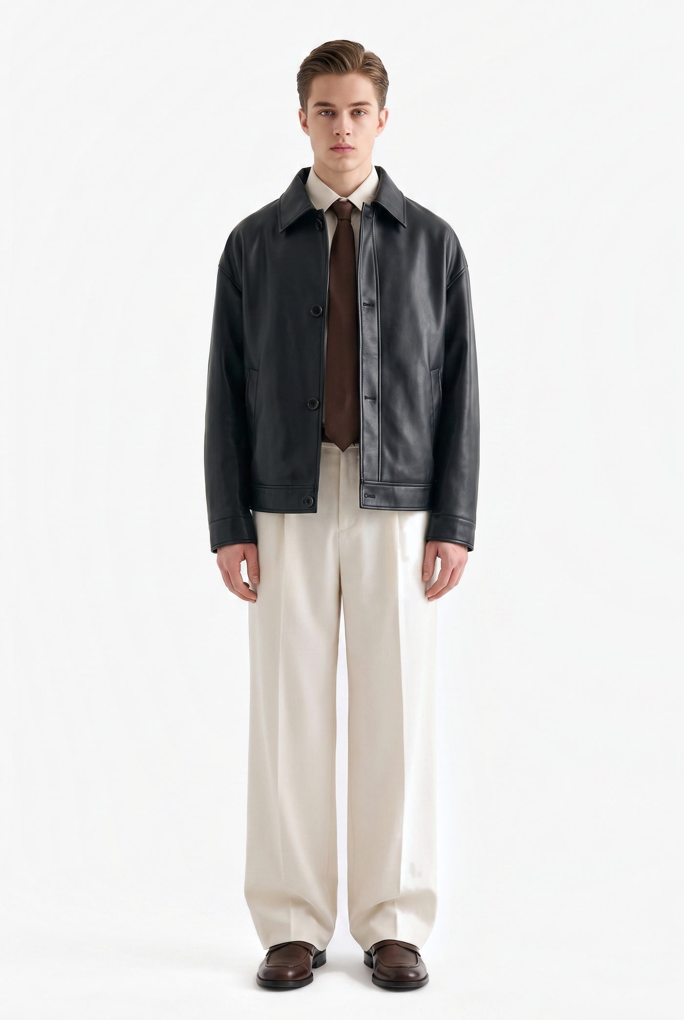 Man in a black leather jacket over a brown tie and cream wide leg trousers